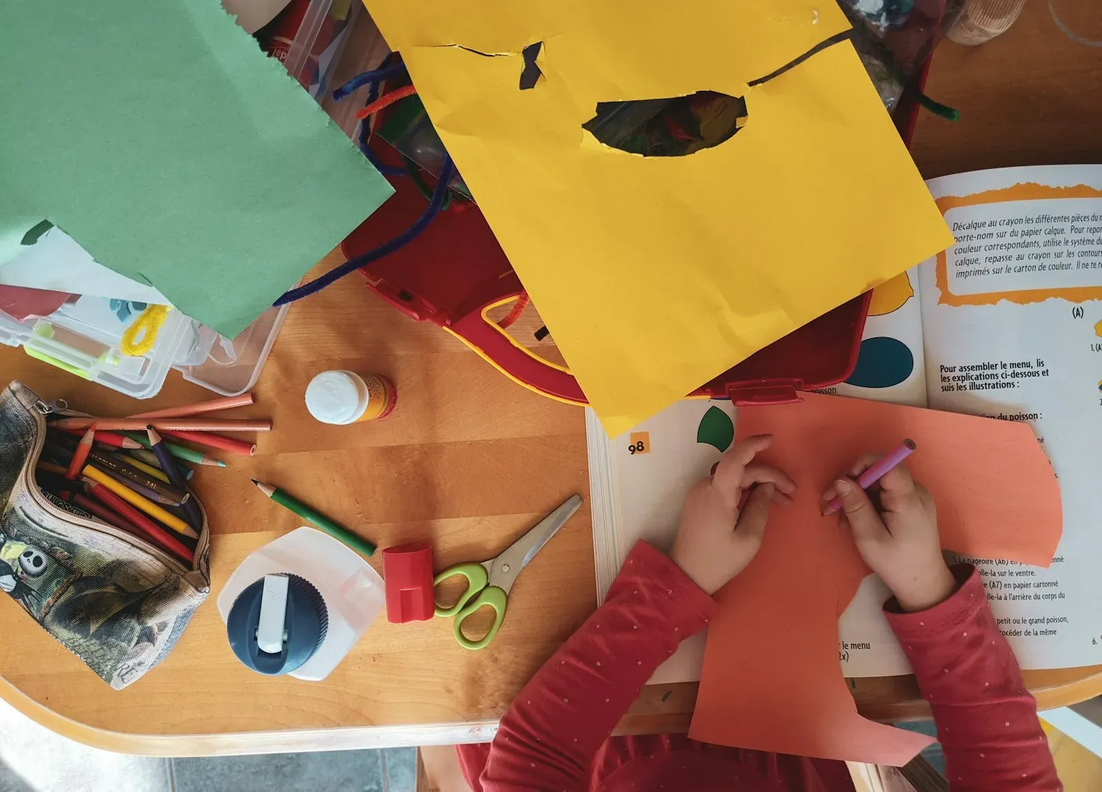 Mani di un bambino che ritagliano carta colorata durante un laboratorio